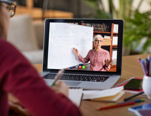 Uma aluna assistindo uma aula pelo computador e fazendo anotações