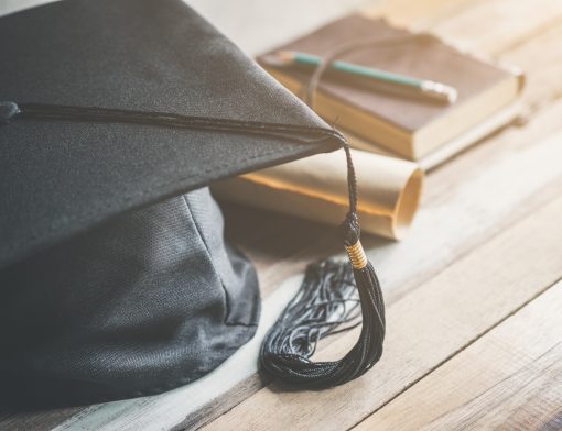 Um chapéu de formatura, um diploma e um caderno com um lápis