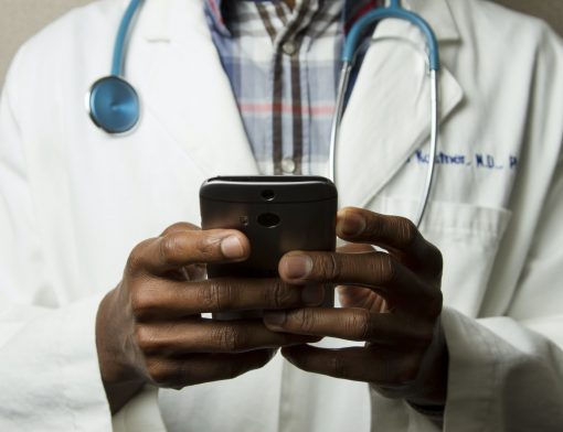 Médico com jaleco mexendo no celular