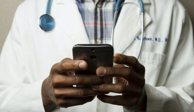 Médico com jaleco mexendo no celular