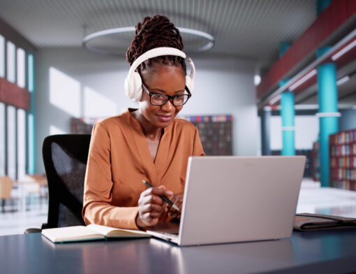 Mulher negra mexendo em seu notebook em ambiente corporativo