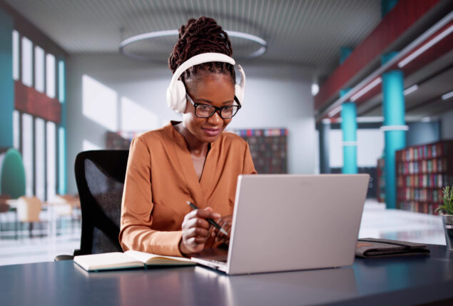 Mulher negra mexendo em seu notebook em ambiente corporativo
