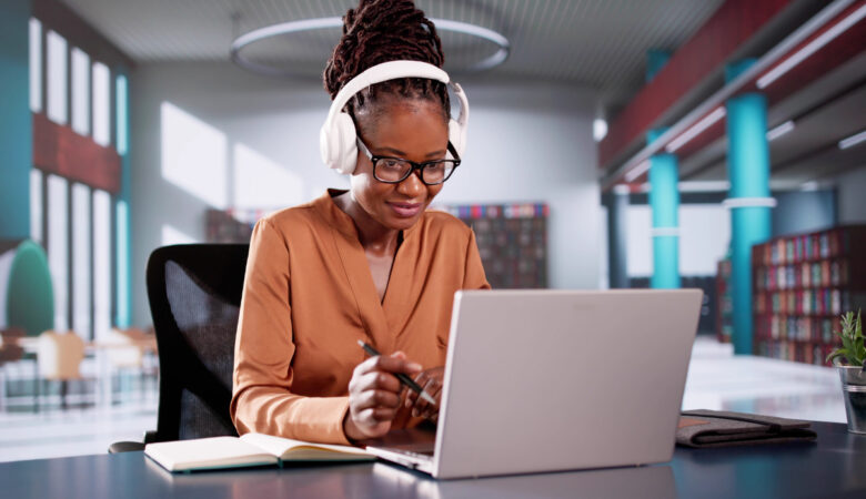 Mulher negra mexendo em seu notebook em ambiente corporativo