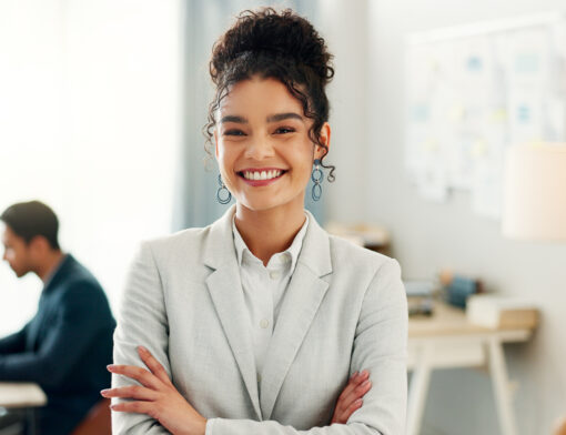 Mulher com cabelo preso em coque e roupa social sorrindo para foto