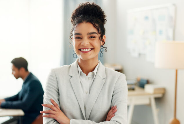 Mulher com cabelo preso em coque e roupa social sorrindo para foto